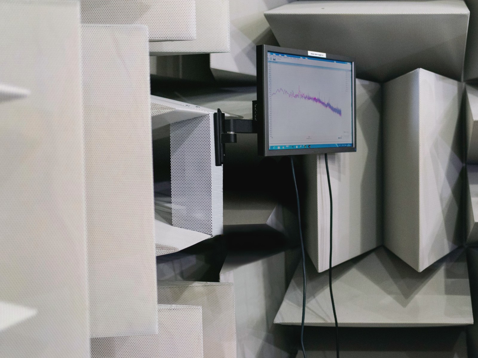 Anechoic chamber with acoustic wedges and a spectrum readout — representative image