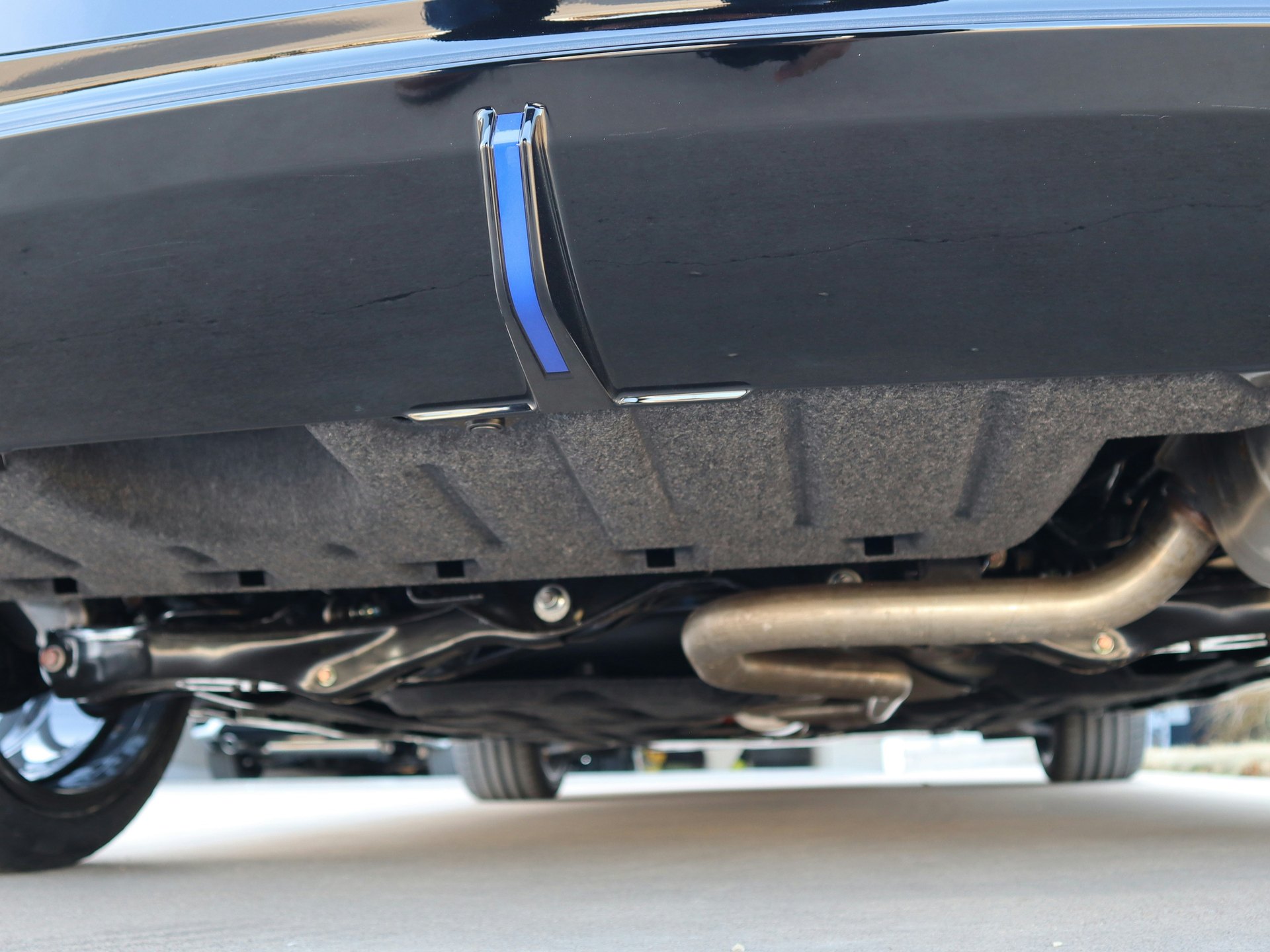 Molded felt underbody panel on a modern car, seen from behind at ground level — representative image