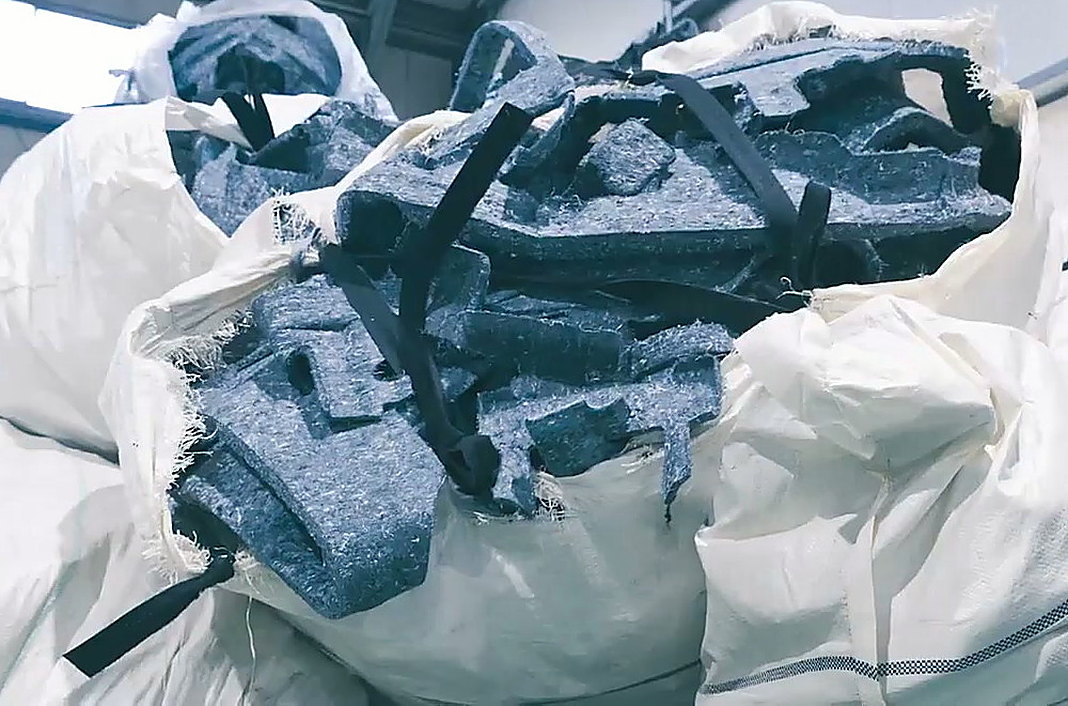 Gray felt offcuts recovered from trimming, bagged for re-opening